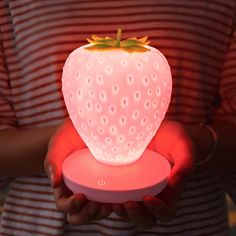 a person holding a lit up strawberry shaped object