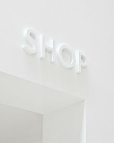 a white shop sign mounted to the side of a wall