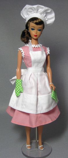 a doll wearing a white and pink dress with green polka dots on the collarline