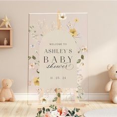 a baby shower sign with flowers and leaves on it in front of a teddy bear