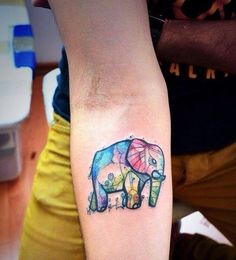 an elephant tattoo on the left forearm and right arm, with watercolor paint splatters all over it