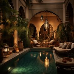 an indoor swimming pool surrounded by greenery and candles lit up at night with lanterns on the ceiling