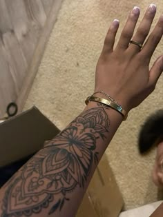 a woman's arm with tattoos on it and a gold band around her wrist