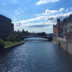 a river running through a city with tall buildings on both sides and a bridge in the distance