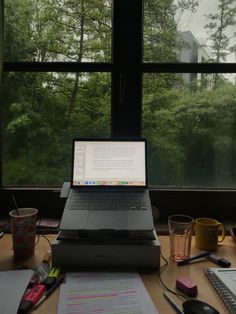 an open laptop computer sitting on top of a desk next to a cup and pen