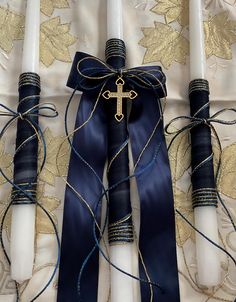 two candles with blue ribbons tied around them and a cross on the top one candle