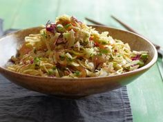 a wooden bowl filled with coleslaw salad on top of a green table cloth