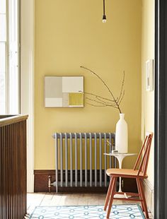 a chair sitting in front of a radiator next to a wall with a painting on it