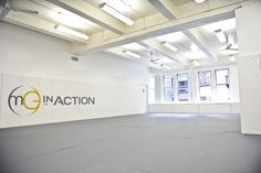 an empty room with the word in action painted on the wall and ceiling lights above it