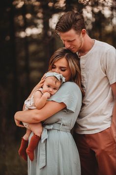 a man and woman holding a baby in their arms