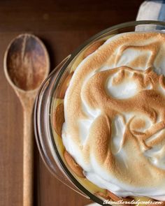 there is a pie with whipped cream on it and a wooden spoon next to it