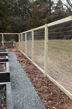 the fence is made of wood and wire, along with some gravel on the ground