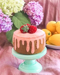 a cake sitting on top of a blue plate next to flowers and lemons in the background