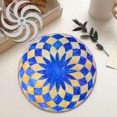 a blue and yellow plate sitting on top of a white table next to a cup