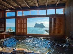 an indoor jacuzzi in the middle of a room with large windows looking out onto the ocean