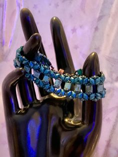 a hand is holding onto a bracelet with blue beads and glass cubes on it