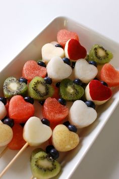 fruit skewers with kiwi, oranges and bananas on a white plate