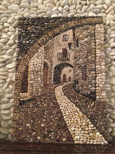 a mosaic is displayed on the wall in front of a stone building with cobblestones