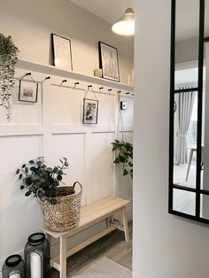 a room with some plants and pictures hanging on the wall next to a wooden bench