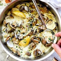 a pan filled with clams and lemons on top of a white countertop