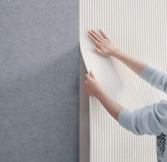 a person is placing their hand on the wall next to a gray carpeted surface