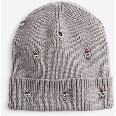 a grey beanie hat with pom poms