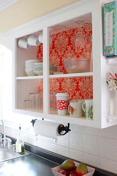 a bowl of fruit sitting on top of a kitchen counter next to an open cabinet