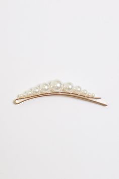 Opt for an elegant statement with a gold-toned hair clip, adorned with white faux pearls.