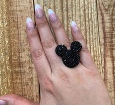 a woman's hand holding a black mickey mouse ring