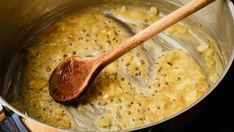 a wooden spoon in a pot filled with some kind of food that is being cooked