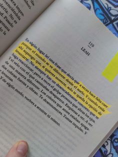 a hand holding an open book with yellow highlight on it