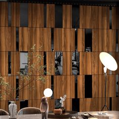 a room with a table, lamp and vases on the tables in front of a wooden paneled wall