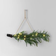 a christmas wreath with lights hanging from the side on a string and attached to a wall