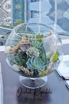 a glass bowl filled with succulents on top of a table