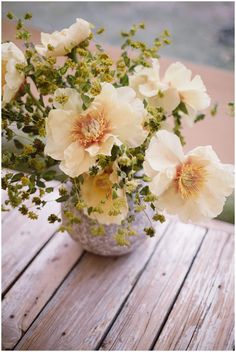 a vase filled with white flowers on top of a wooden table