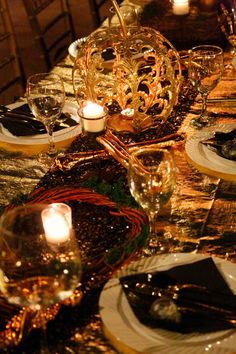 the table is set with candles, plates and silverware for an elegant dinner party