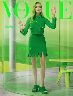 a woman in a green dress is posing for a magazine cover with her hands up