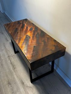 a wooden table sitting on top of a hard wood floor next to a white wall