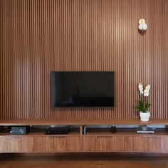 there is a television on the wall in this living room with wood paneling and white flowers