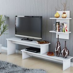 a flat screen tv sitting on top of a white shelf next to a vase filled with flowers