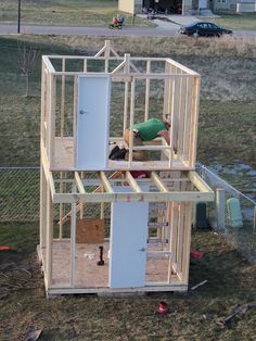 a man is working on the inside of a chicken coop that's being built