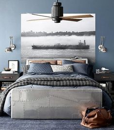 a bedroom with blue walls and a large painting on the wall above the headboard