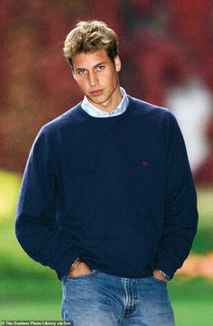 the young man is wearing a blue sweater and standing in front of a soccer field