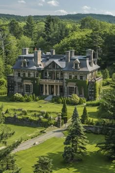 an aerial view of a large house surrounded by trees and grass in the middle of a wooded area