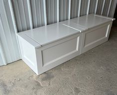 a white storage bench sitting in front of a metal wall next to a garage door