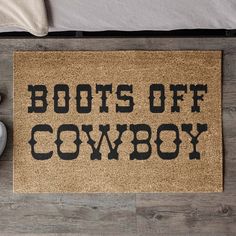 a door mat with the words boots off cowboy written on it next to a pair of shoes