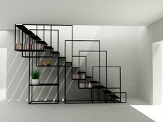 a set of black shelves with books and vases on them in an empty room