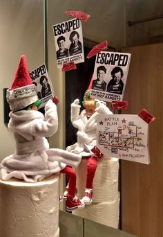 two white toilet paper rolls decorated with red and green elf hats on top of each other