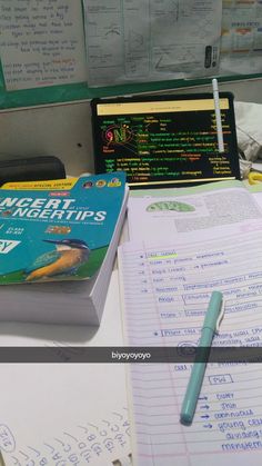 a book sitting on top of a desk next to a pen and laptop computer monitor