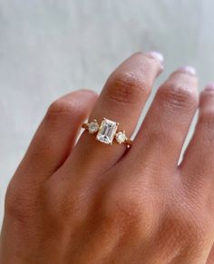 a woman's hand with a diamond ring on top of her finger and an engagement band